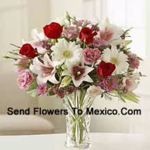 Roses rouges, œillets roses, géraniums blancs et lys blancs avec d'autres fleurs assorties dans un vase en verre